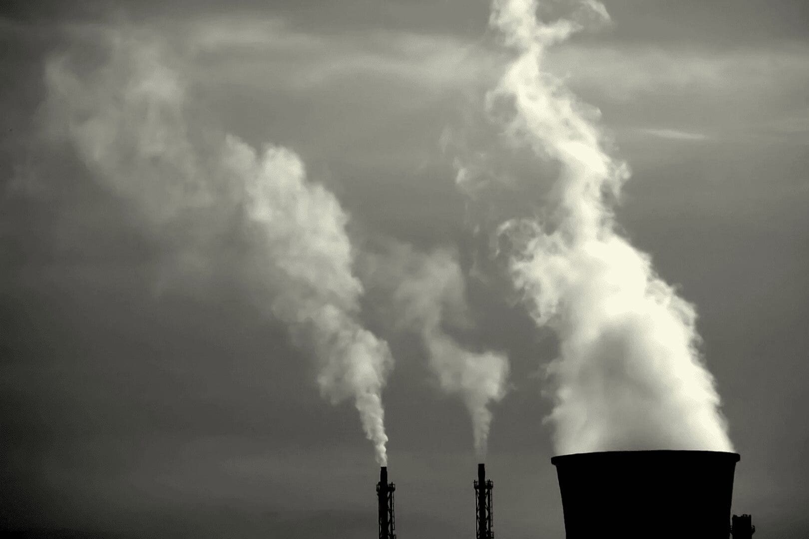 A black and white photo of smoke coming out from two towers.