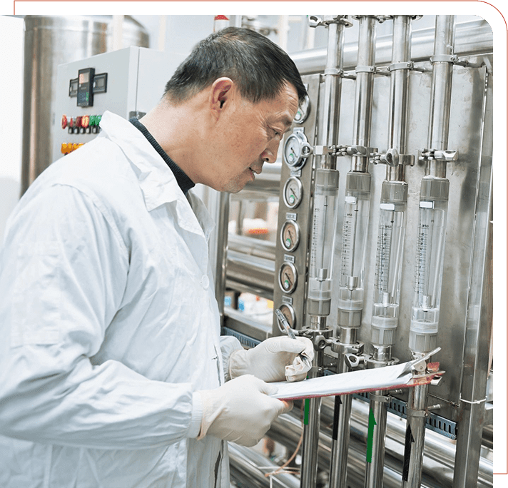 A man in white lab coat writing on paper near machine.